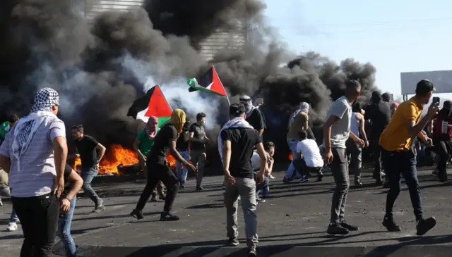 Palestinian protesters throw stones during clashes with Israeli troops at Huwwara checkpoint near the West Bank City of Nablus, 18 May 2021