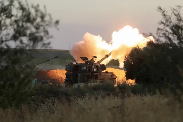 Israeli soldiers work in an artillery unit as it fires near the border between Israel and the Gaza strip, on the Israeli side