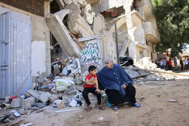 Palestinians sits amidst debris in the aftermath of Israeli airstrikes