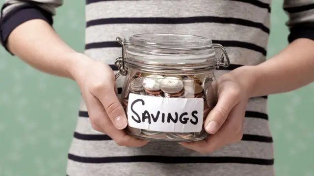 Woman holding a money jar marked 'savings'