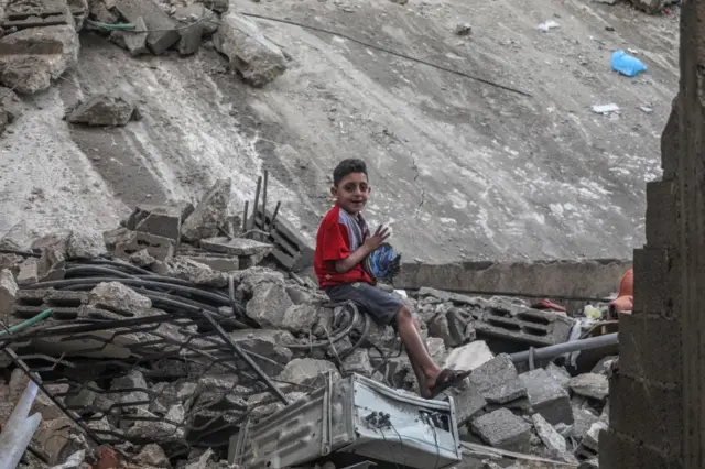 A Palestinian boy sits at the rubble of the destroyed house in Gaza