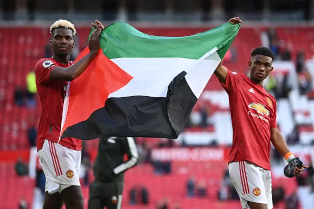 Paul Pogba and Amad Diallo of Manchester United applaud the fans whilst holding a Palestine flag after the Premier League match between Manchester United and Fulham at Old Trafford on May 18, 2021