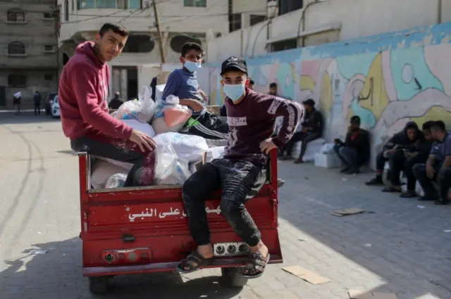 Palestinian boys ride on a motorised rickshaw loaded with food supplies in Gaza