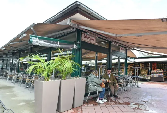 An elderly couple rests in front of a closed restaurant at the Naschmarkt market in Vienna on May 18, 2021, as restaurants and hotels plan to re-open