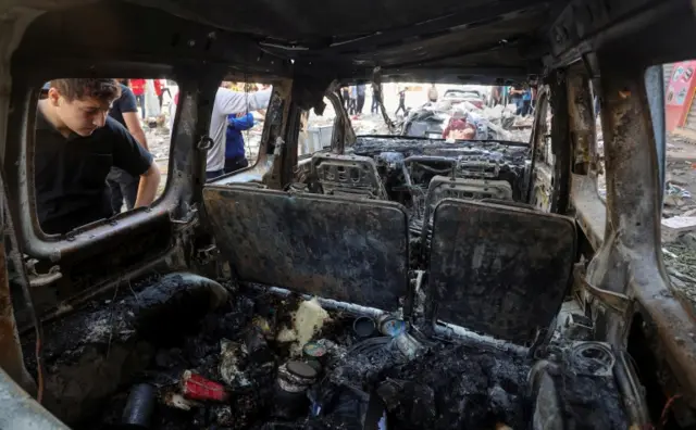 A Palestinian looks at a destroyed vehicle following an Israeli air strikes on a house in Gaza City. Photo: 19 May 2021