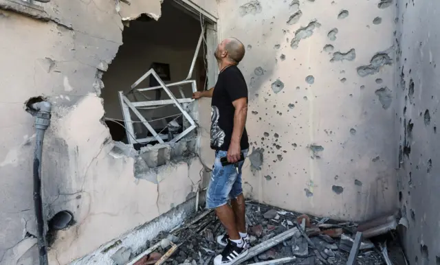 Amir Buchbut looks at his damaged house after it was hit with a rocket fired from Gaza to Sderot, Israel, May 20, 2021.