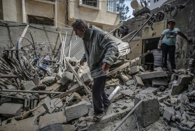 A Palestinian inspects his destroyed house after Israeli air strikes in Gaza City