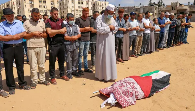 Palestinians pray over the body of 32-year-old Huda Khazandar, killed in an Israeli airstrike that also wounded her husband and neighbours, in Khan Yunis, in the southern Gaza Strip, on May 20, 2021.