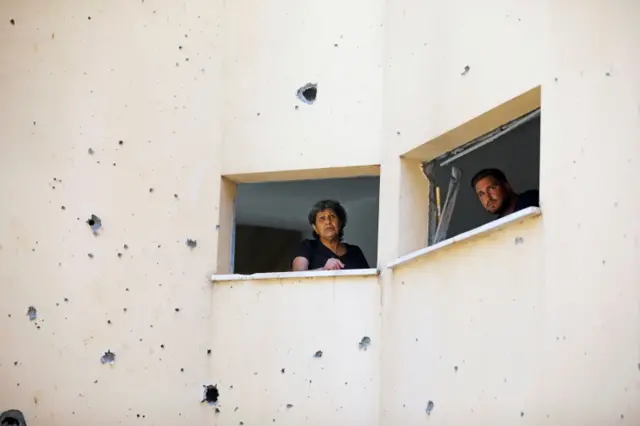 People look out from a building damaged after a rocket fired from the Gaza Strip last week landed nearby, in Petah Tikva, Israel on 20 May 2021