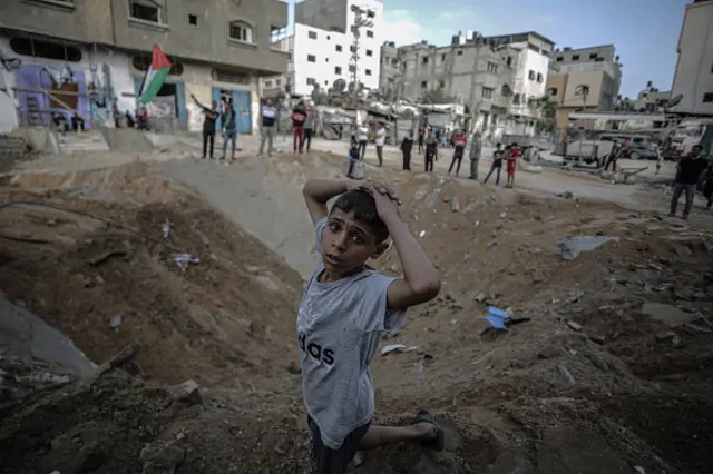 Palestinians inspect a hole after Israeli strike damaged streets in Gaza City, Gaza on May 20, 2021.