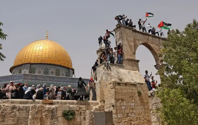 Palestinian Muslim worshippers wave the Palestinian and the Hamas flag during clashes with Israeli security forces in Jerusalem's al-Aqsa mosque compound, the third holiest site of Islam, on May 21, 2021