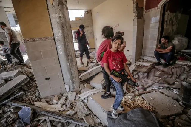 Palestinian girls stand in the rubble of their destroyed house