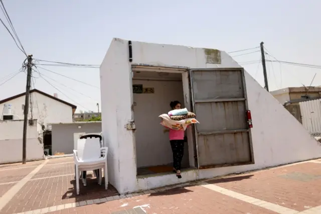 An Israeli girl carries her sleeping items as she walks out of a public bomb shelter