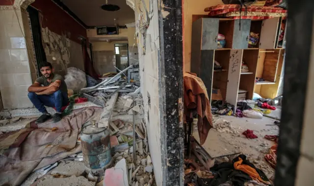 A Palestinian sits in the rubble of his destroyed house