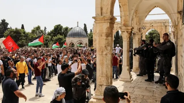 Israeli police stand as Palestinians protest at the al-Aqsa mosque compound in occupied East Jerusalem (21 May 2021)