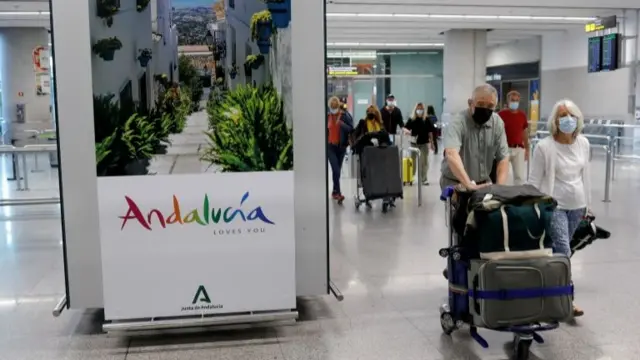 Tourists wearing protective face masks walk with their luggage as they arrive at Malaga-Costa del Sol Airport, in Malaga, Spain, May 24, 2021