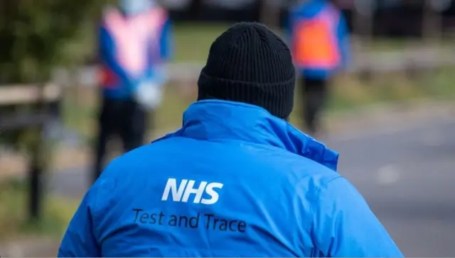 An NHS Test and Trace logo on a member of staff"s jacket - generic