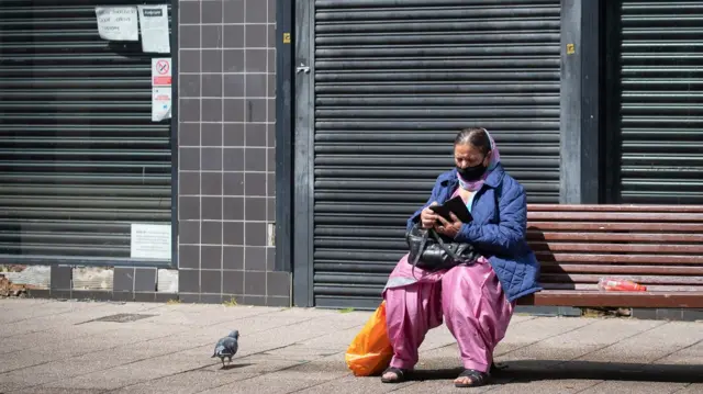 A woman sitting on a bench in Bedford