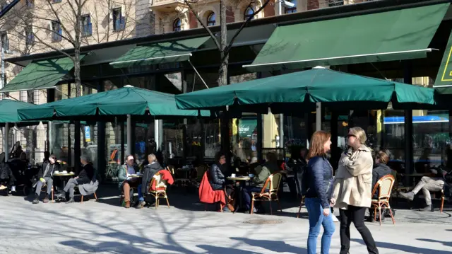 People sit outside a restaurant in Sweden