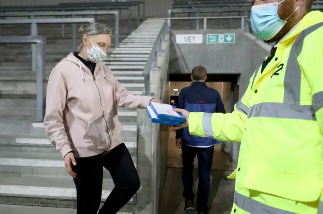 Stewards hand out lateral flow tests to fans as they leave the stadium, after the Betfred Super League match at The Totally Wicked Stadium, St Helens