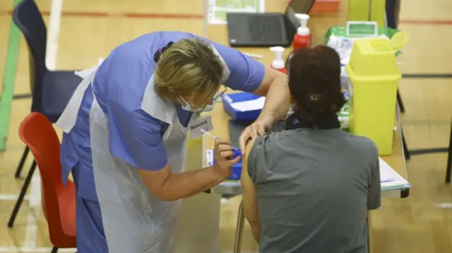 A member of the public receives a dose of the Oxford/AstraZeneca vaccine at Cwmbran Stadium in south Wales