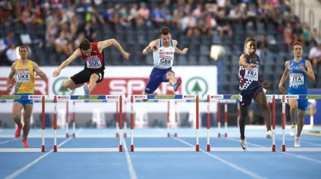 Athletes jump over the hurdles