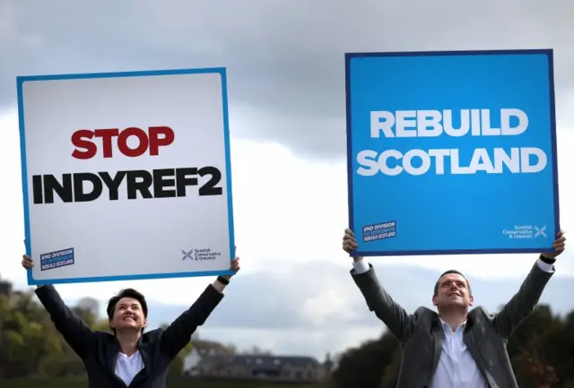 Ruth Davidson and Douglas Ross hold up placards in front of Stirling Castle