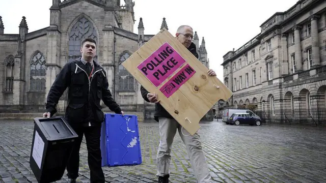 Men carrying ballot boxes and polling place sign