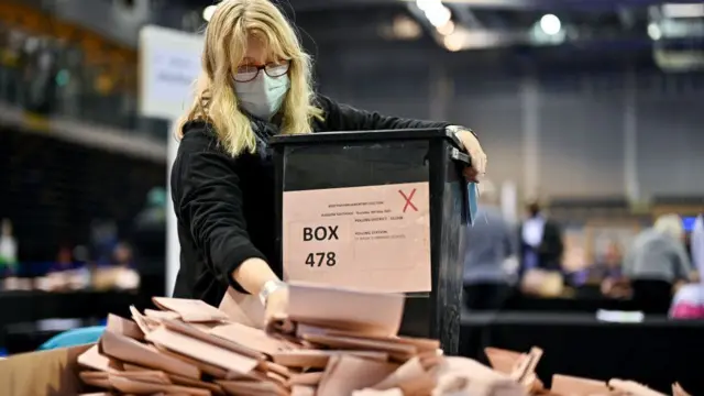 A woman empties a box of ballot papers