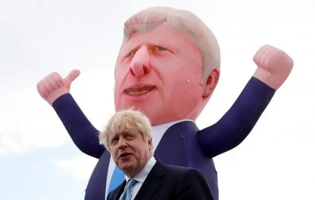 Boris Johnson in front of an inflatable blimp of himself