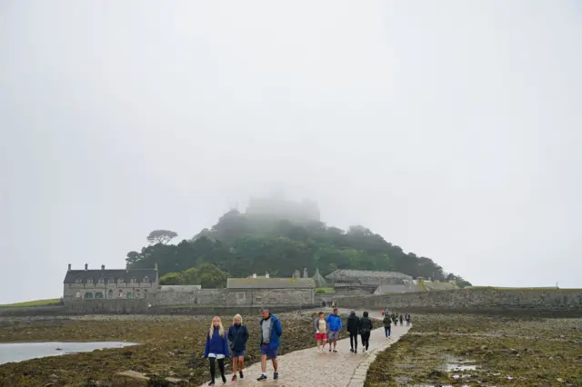 A castle on a hill top, covered in fog