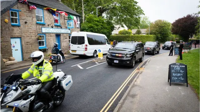 A police motorcade passes a pub