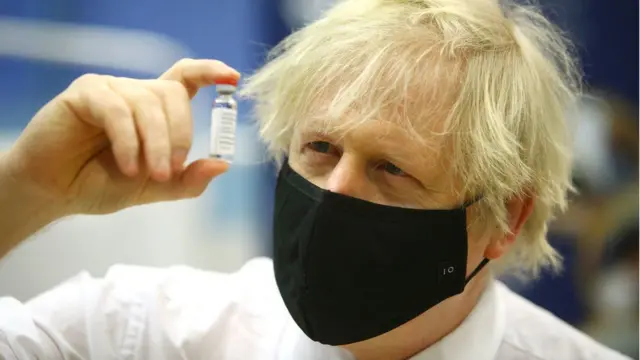 Boris Johnson holds up a vaccine vial