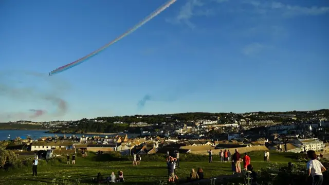 People watch as the Royal Air Force aerobatic team, the Red Arrows, perform over St Ives, during the G7 summit in Cornwall, Britain