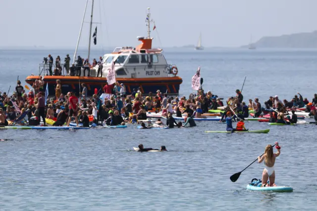 People ride kayaks, boats and surfboards as they hold signs in a protest in Gyllyngvase beach, Falmouth, during the G7 summit in Cornwall, Britain