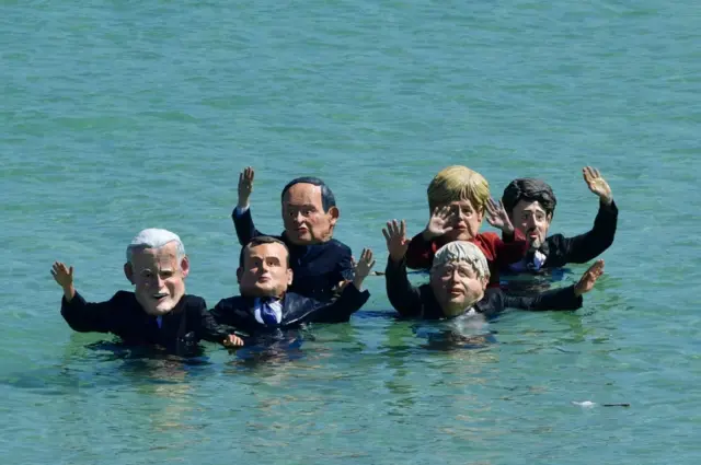 Extinction Rebellion protesters, wearing masks of G7 leaders in the sea in St Ives, during the G7 summit in Cornwall.