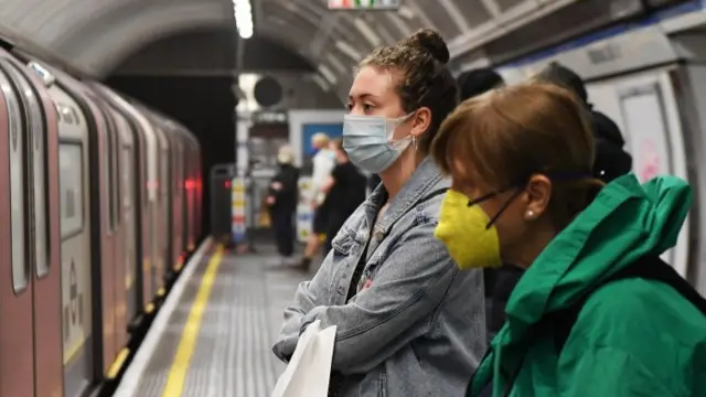 Passengers wait for a train on London's underground during the Covid pandemic