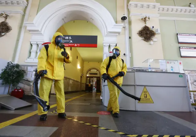 Employees of the Lider Centre for Special Risk Rescue Operations of Russia's Emergencies Ministry in protective suits disinfect Moscow's Rizhsky railway station