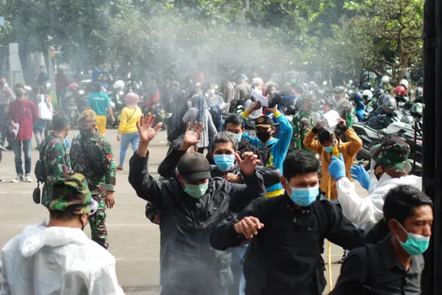 Health workers spray disinfectant on people arriving to get vaccinations against the Covid-19 coronavirus at a makeshift mass vaccination centre at a stadium in Bandung on June 17, 2021