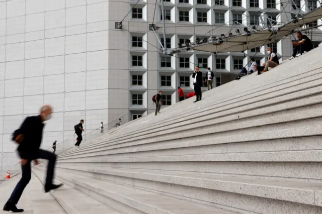 People wearing protective face masks walk at the financial and business district of La Défense in Nanterre in France, on 10 June 2021