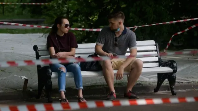 Two people sit on a bench in a Moscow park