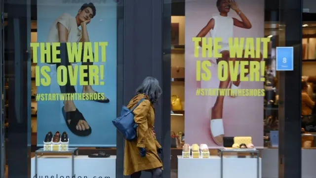 A woman walks past a shop window