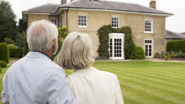 A man and a woman staring at a large house