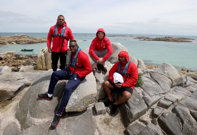 Lions players pose for a photo on some rocks by the sea