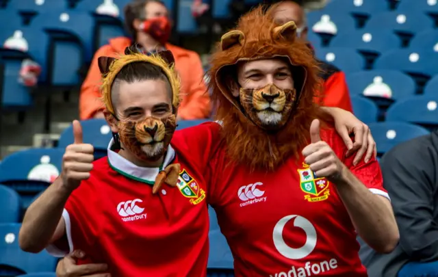 Two Lions fans wearing manes and lions face masks