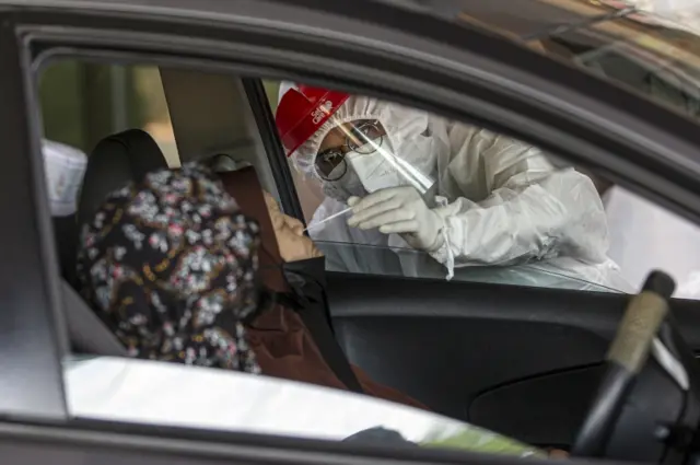 A woman undergoes a swab test at a drive-through testing centre in Kuala Lumpur, Malaysia, on 26 June 2021