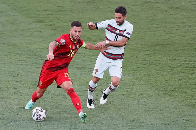 Eden Hazard holding off a Portugal player