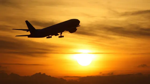 A plane takes off at sunset