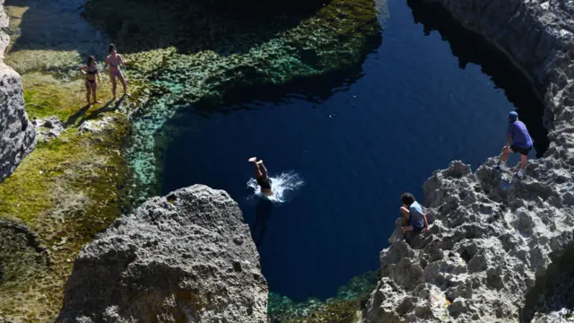 People dive into water at Gozo Island in Malta