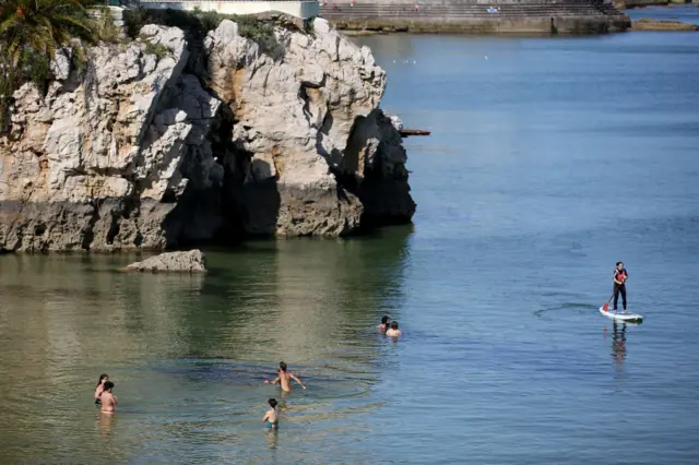 People swim at the beach in Cascais, Portugal